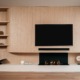 een luxe japandi cinewall in een licht eiken kleur met een tv, soundbar en elektrische haard.