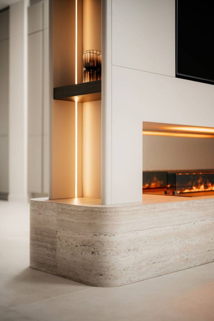 Een moderne open haard met een door glas omsloten vlam staat op een gladde stenen voet, naadloos geïntegreerd in een slanke Cinewall. Warme verticale verlichting accentueert het decoratieve glas erboven en creëert een gezellig en minimalistisch interieur.
