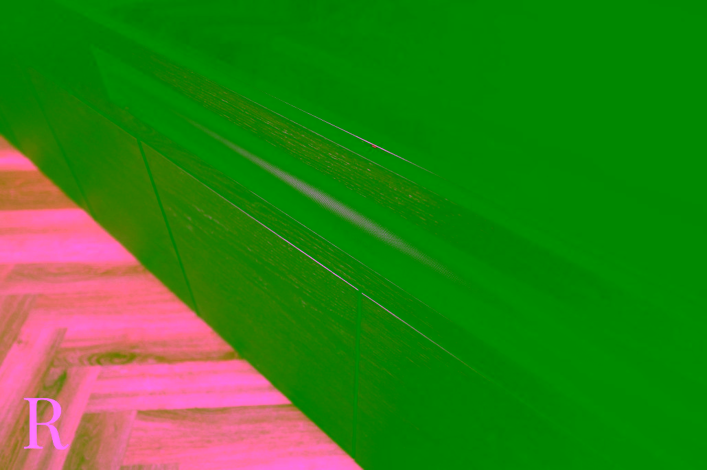 Een close-up van een zwarte Sonos soundbar op een donkerhouten tv-meubel, met een lichte visgraat houten vloer eronder.