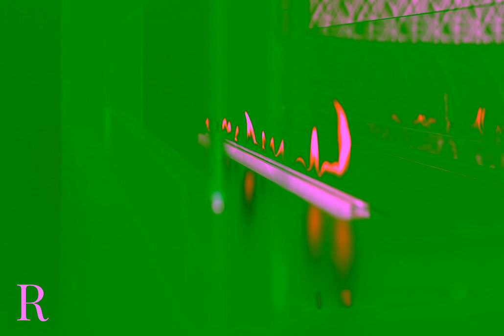 Een close-up van een moderne lineaire open haard met kleine, heldere vlammen achter heldere glazen panelen. De omgeving ziet er elegant en eigentijds uit, met een muur met textuur zichtbaar op de achtergrond.